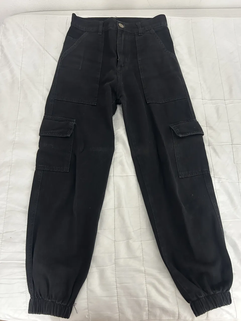 Pantalón cargo negro tiro medio, con bolsillos laterales y puño elastizado en la botamanga. Ideal para un look urbano y canchero.