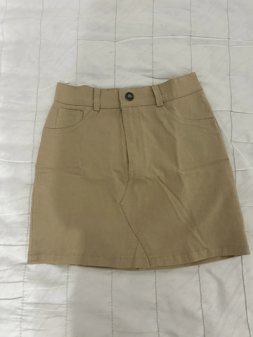 Pollera de gabardina color tiza, tiro alto, con bolsillos y detalles de costura. Un básico súper canchero para armar looks divinos.