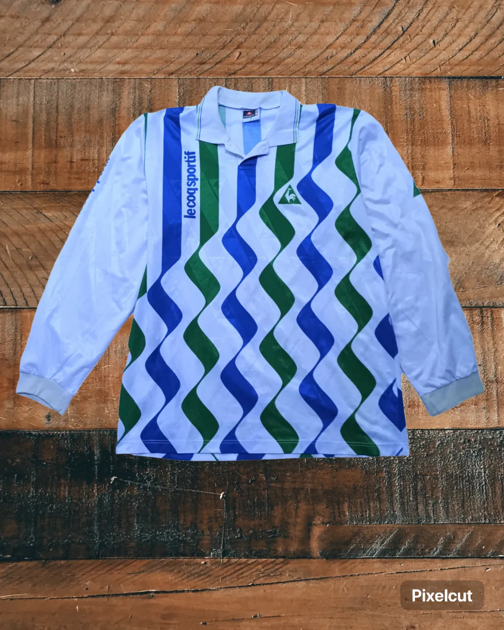 Remera manga larga deportiva vintage de Le Coq Sportif, con un diseño de rayas verticales y ondas en azul y verde. Ideal para un look retro y canchero.