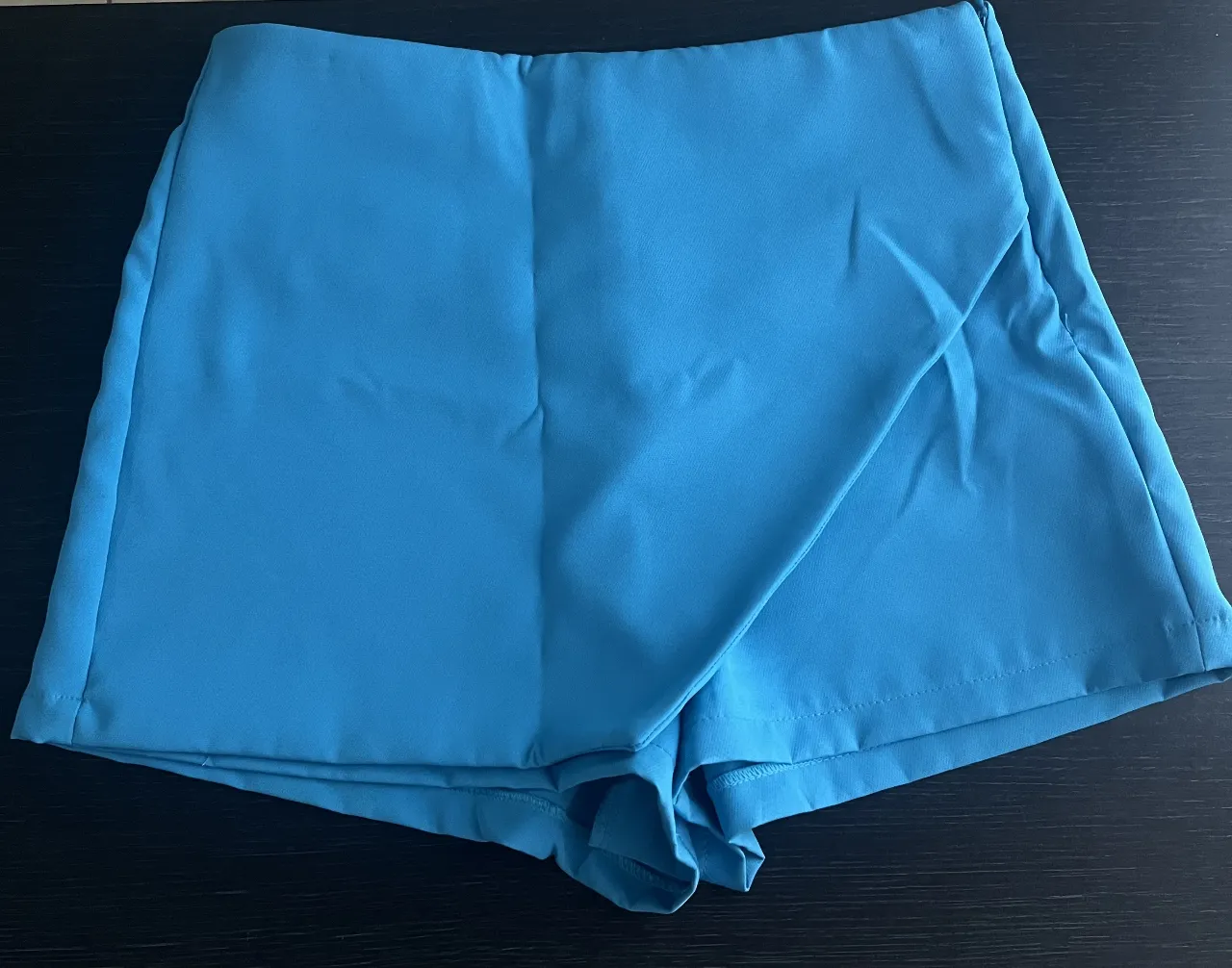 SKORT/ shortpollera de mujer color turquesa . Diseño con solapa cruzada en la parte delantera y bolsillos traseros. Ideal para un look moderno y fresco.

La prenda esta arrugada por estar guardada, pero se entrega planchada 😊