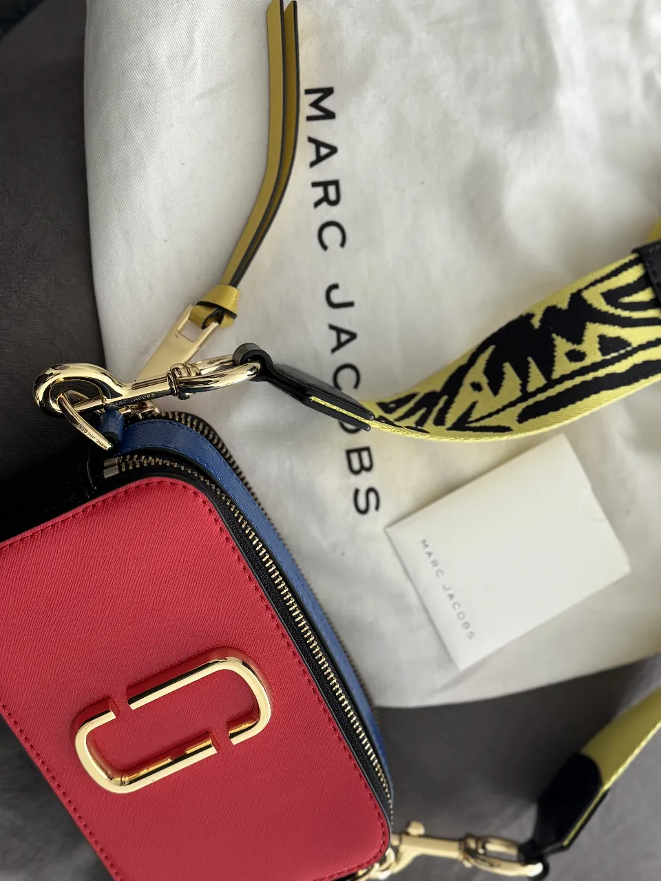 Cartera bandolera rectangular de cuero sintético, con detalles en amarillo y negro. Posee correa ajustable y cierre con cremallera. Ideal para un look moderno y urbano.