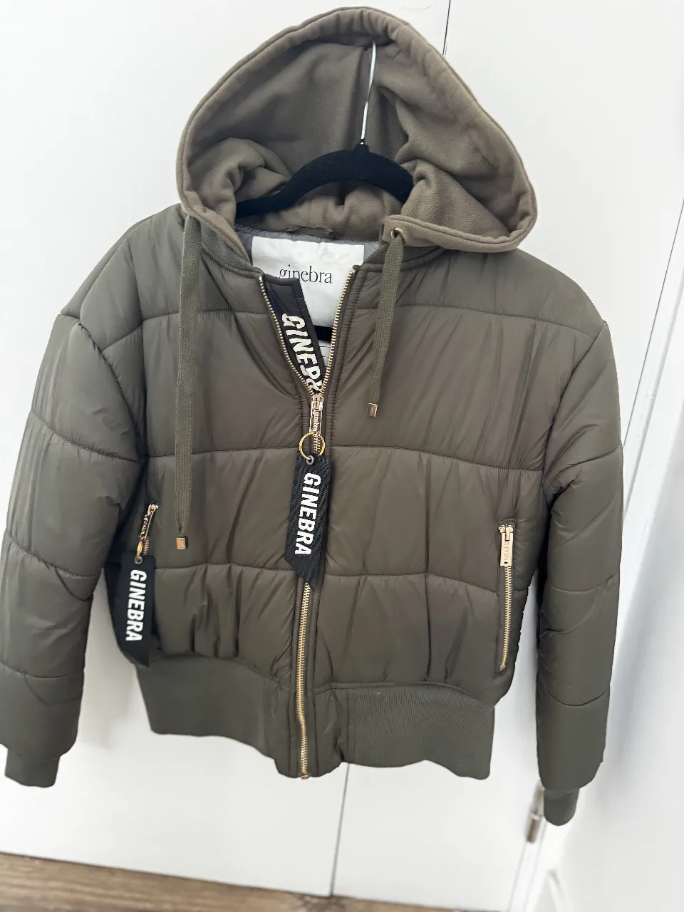 Campera puffer verde oscuro con capucha, cierre y bolsillos con cierre dorado. Ideal para el invierno. Marca Ginebra.