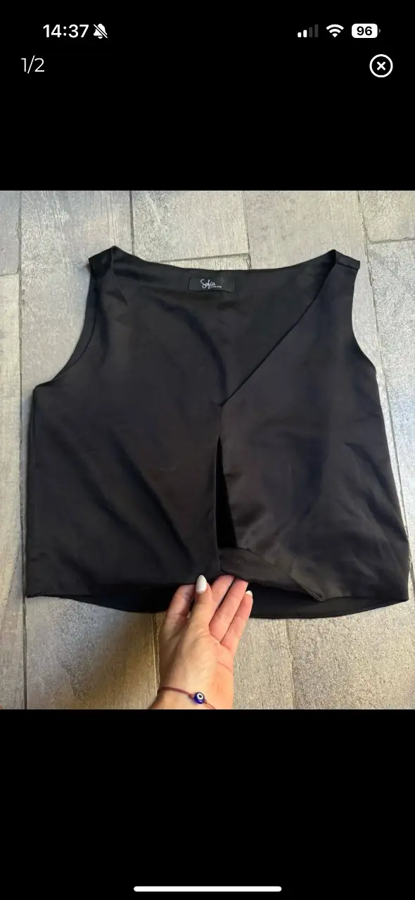 Top negro con escote en V y detalle de abertura frontal. Ideal para un look elegante y moderno.medidss largo total 40, axila a axila 43, hombro a hombro 33. casi sin uso