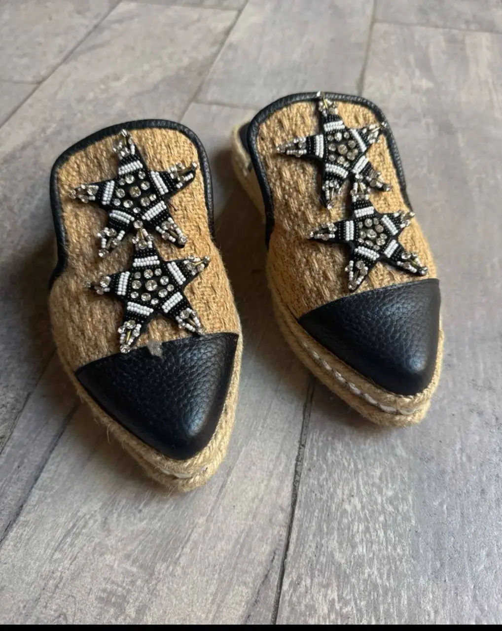 Sandalias planas de mujer, estilo mule, con diseño de estrellas bordadas con pedrería. Capellada de yute y puntera de cuero negro. Suela de yute con detalles de tachas plateadas. Marca Chelaloraa. talle 36 horma chica. sin uso