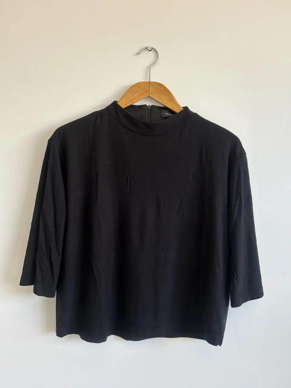 Remera negra Kosiuko manga 3/4 de cuello alto con cierre en la espalda. Calce holgado.