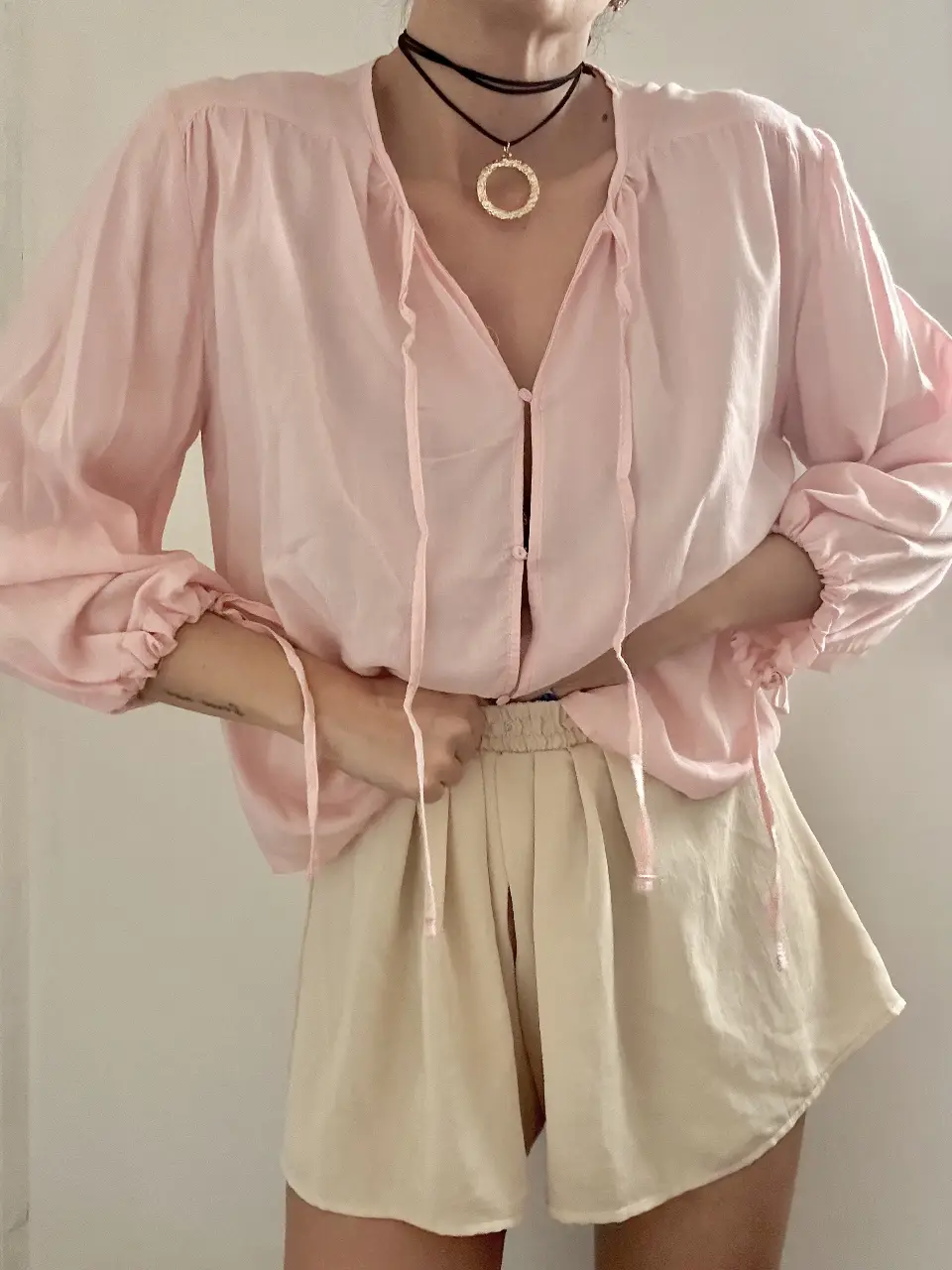 Blusa rosa de manga larga con detalles de lazos y botones. Ideal para un look casual y femenino.
