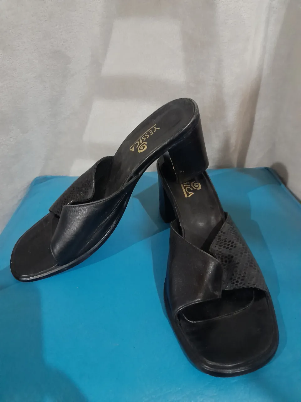 Sandalias negras de taco con tiras cruzadas y detalle de textura tipo reptil.