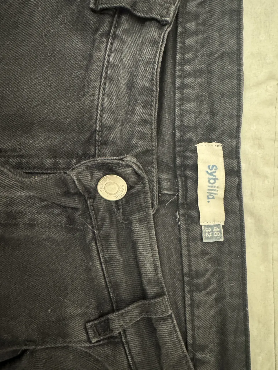 Jeans negro tiro alto, corte ancho, rígido. 
Talle 48, pero yo soy 46 y queda medio ajustadito.
Tiene un detalle de pintura blanca en la pierna izquierda.