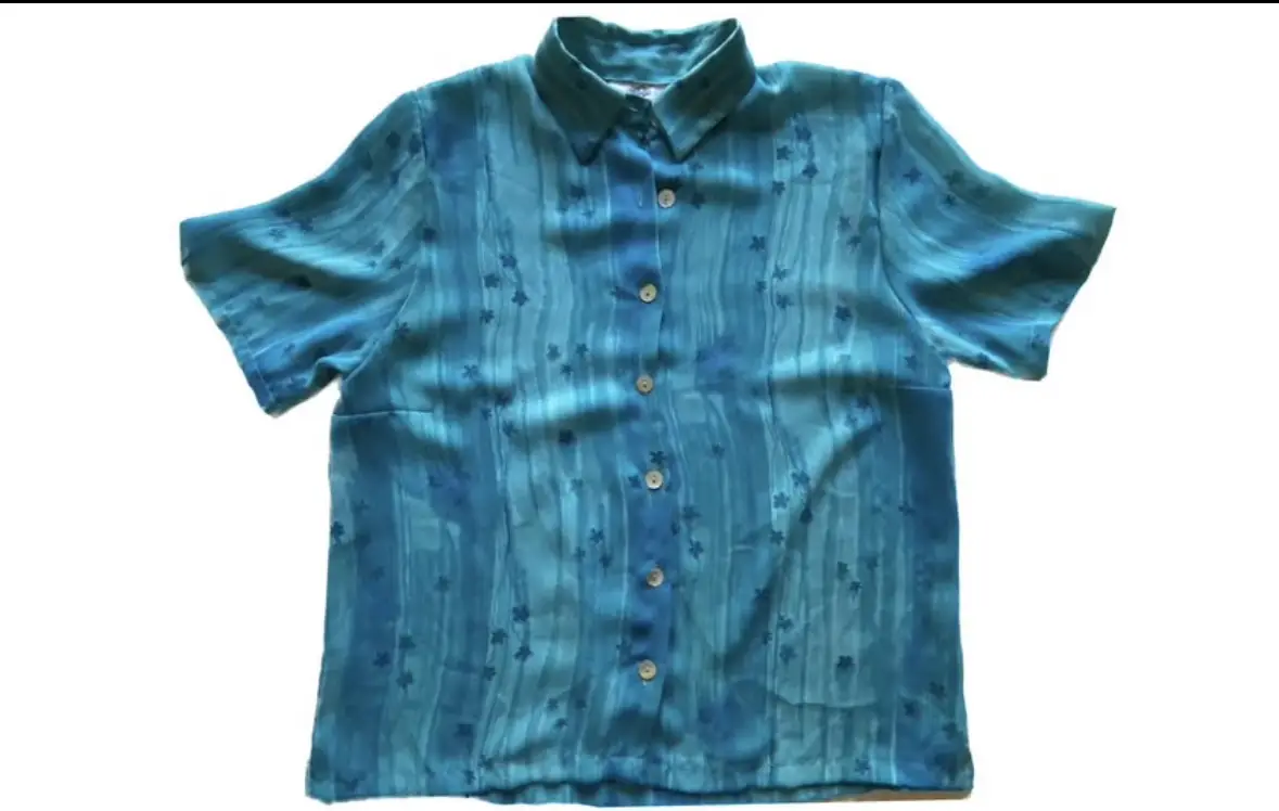 Camisa de mujer vintage con estampado floral en tonos azules. Corte clásico con cuello camisero y mangas cortas. Ideal para un look fresco y con estilo.