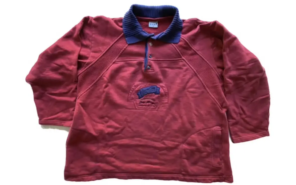 Buzo vintage, color rojo con cuello polera azul marino. Detalles bordados en el pecho. Ideal para un look retro y casual.