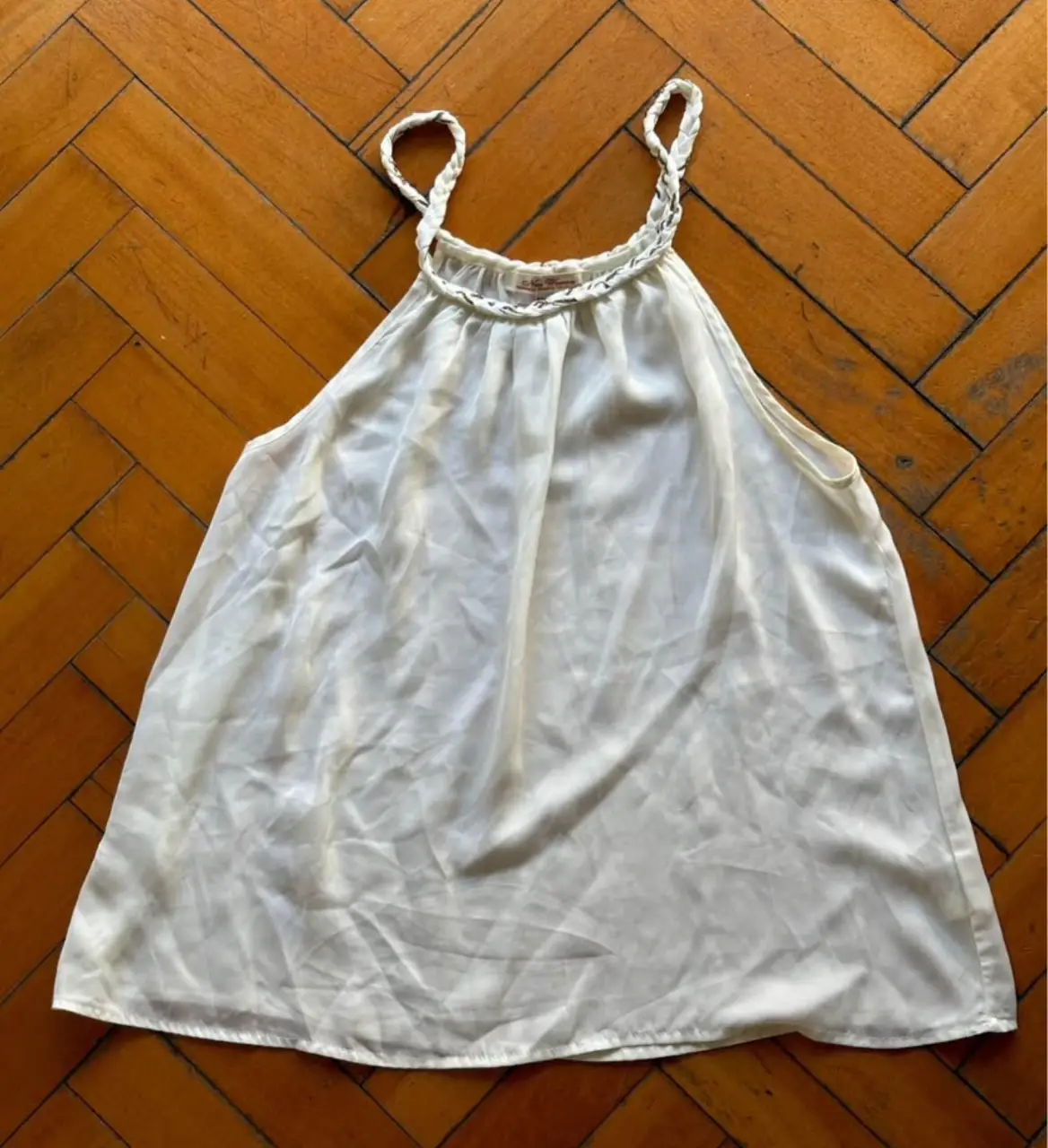 Top blanco de seda con breteles finos y detalle de encaje en el escote. Ideal para un look fresco y elegante.