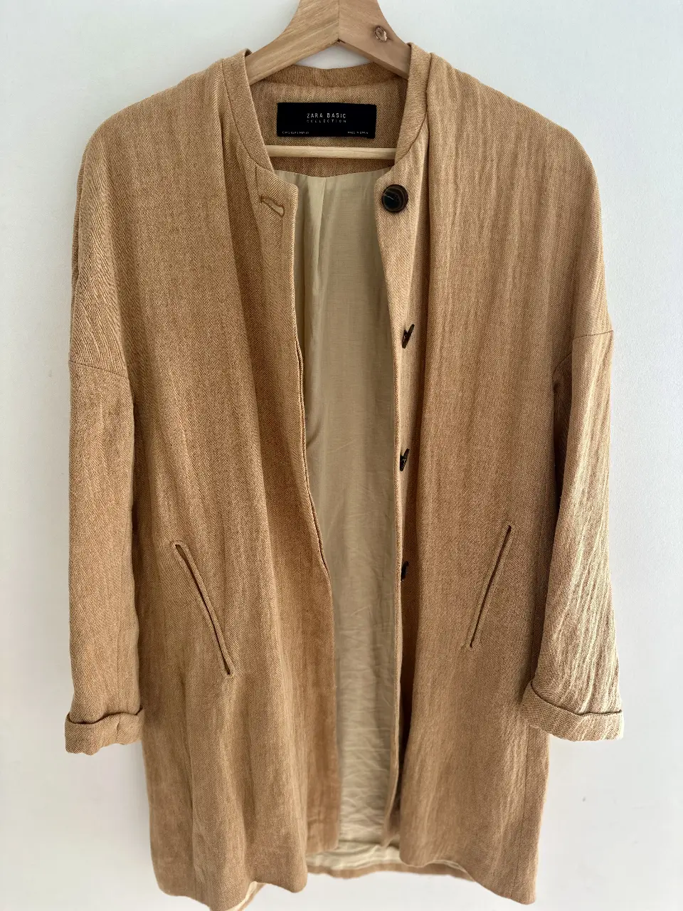 Tapado largo de Zara Basic, color marrón claro, con cuello redondo y botones. Ideal para un look casual y elegante.