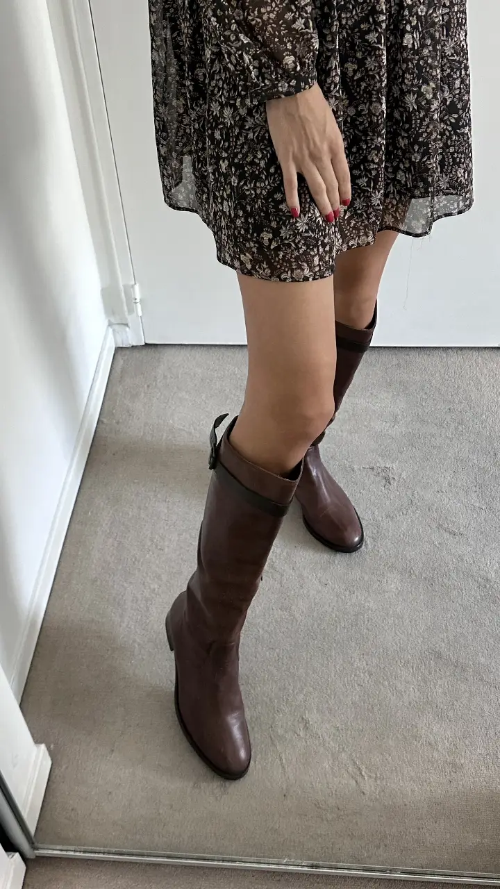 Botas de caña alta de cuero marrón, con cierre lateral y detalles de hebilla. Ideales para un look elegante y abrigado. Un solo uso. Precio original USD 396