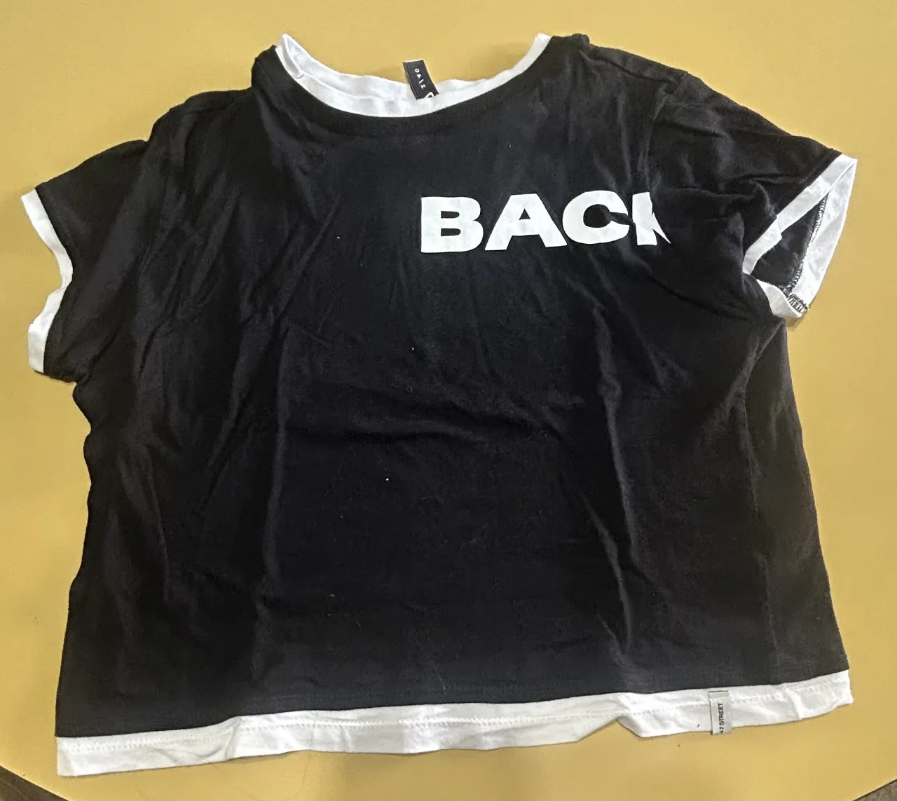 Remera negra de manga corta con detalles en blanco. Estampado "BACK" en el frente y "STAGE." en la espalda. Ideal para un look casual y moderno.
