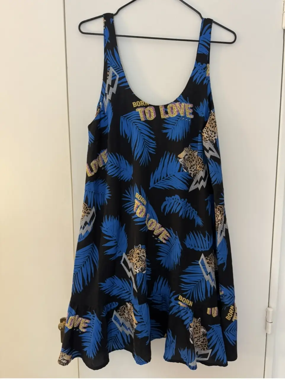 Vestido mini de mujer, con estampado de hojas y detalles de leopardo. Con la frase "BORN TO LOVE" en dorado. Ideal para un look casual y moderno.