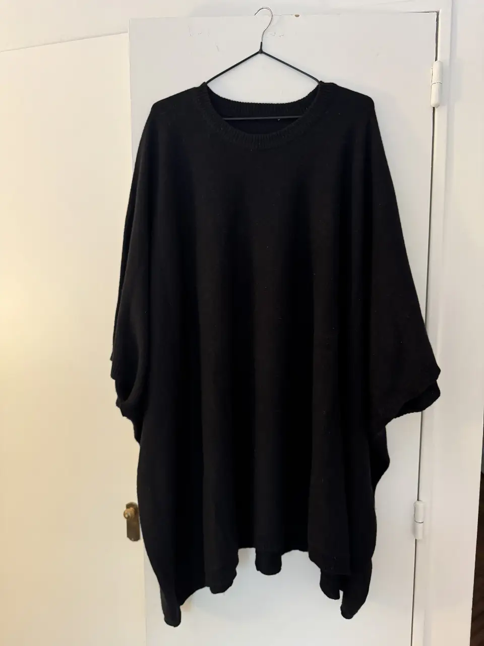Sweater negro de tejido tipo poncho, con mangas amplias y corte holgado. Ideal para un look cómodo y moderno.