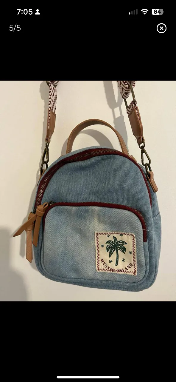 Mochila mini de jean azul con detalles marrones y parche "Mystic Island". Ideal para llevar lo esencial con estilo.