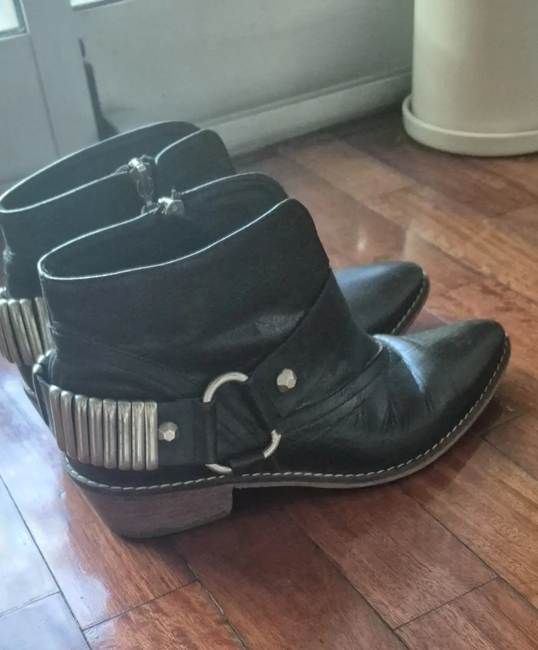 Botines negros de cuero con detalles metálicos en el talón y cierre lateral. Estilo rocker y moderno, ideales para un look audaz.