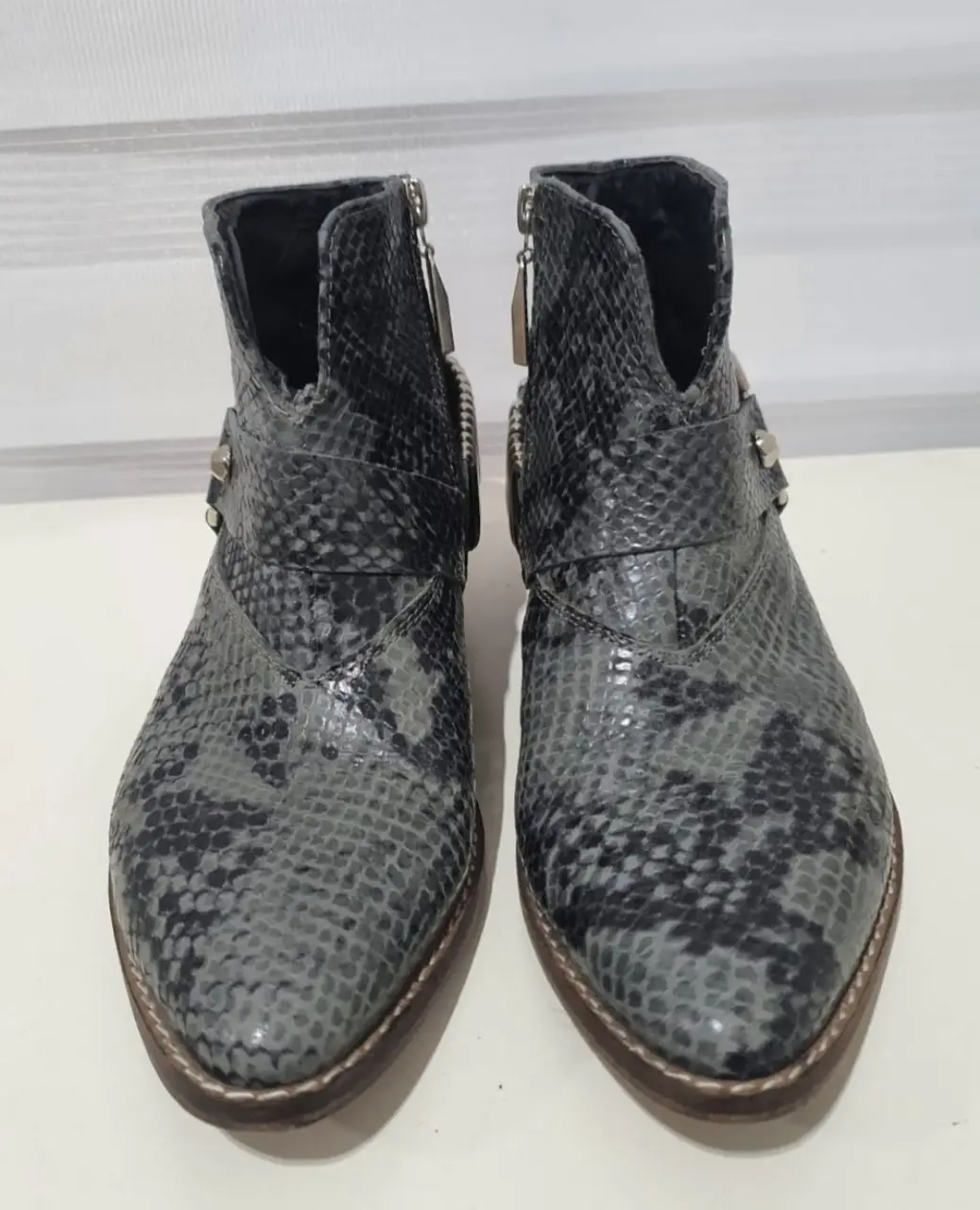 Botinetas de cuero con estampado de serpiente, cierre lateral y detalles metálicos. Ideales para un look moderno y audaz.