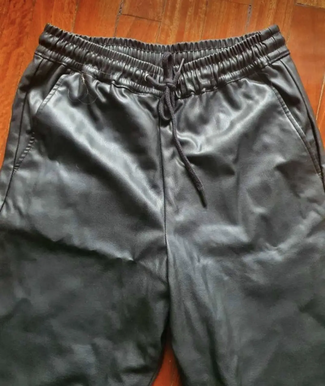 Pantalón de cuero sintético negro, con cintura elastizada y cordón para ajustar. Talle XS, ideal para un look moderno y versátil.
