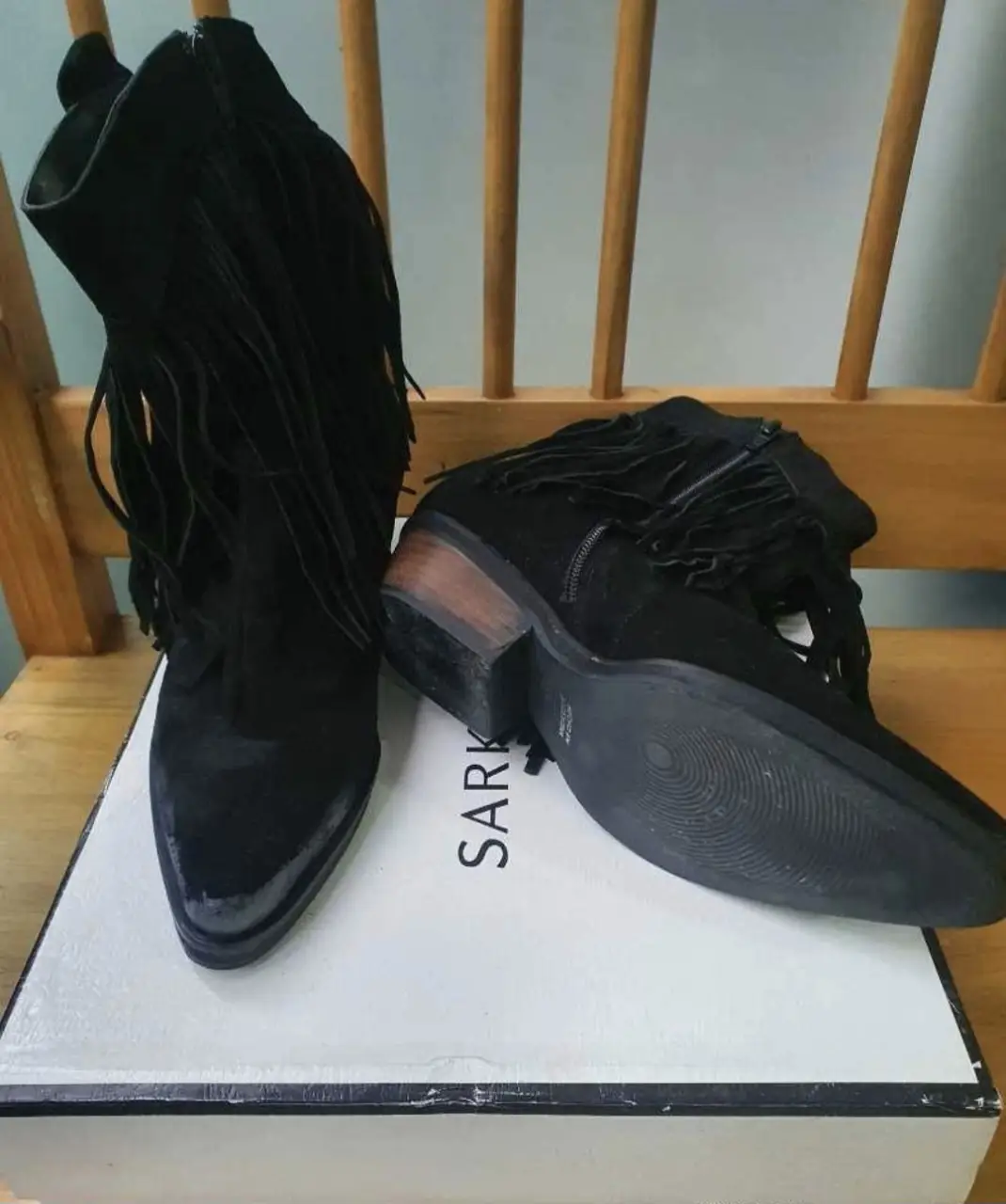 Botines negros con flecos de gamuza, ideales para un look boho o rocker. Tienen un taco bajo de madera y cierre lateral. Perfectos para combinar con jeans, shorts o vestidos.