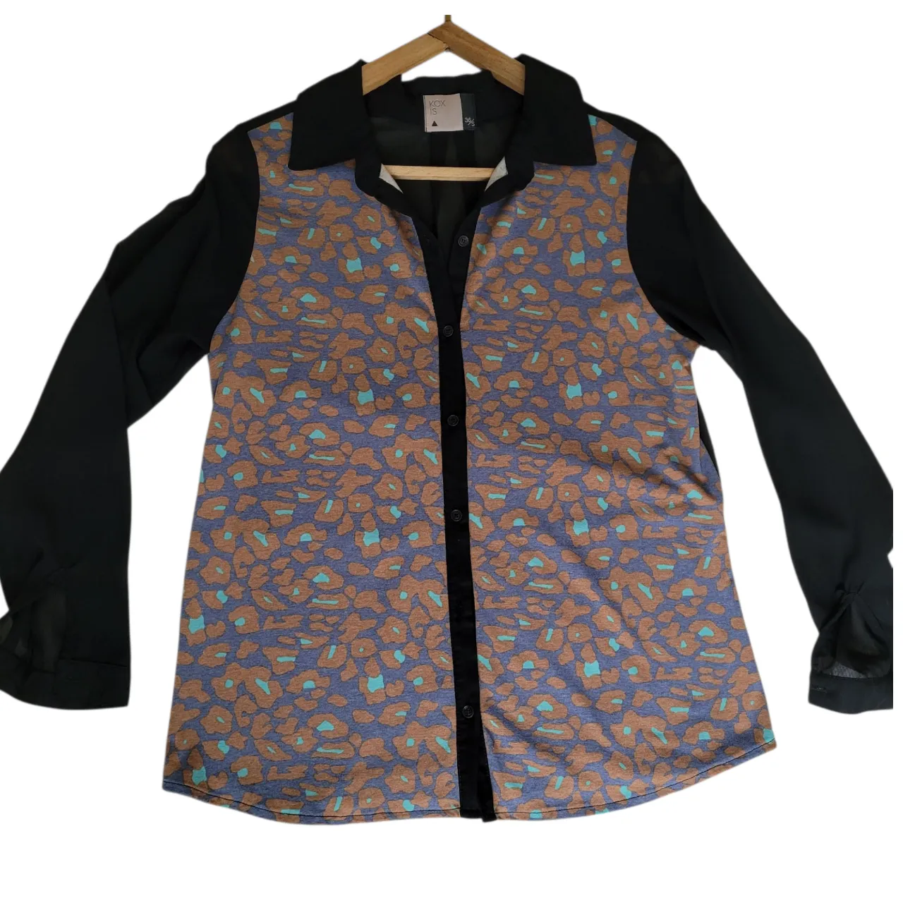 Camisa KOXIS de mujer con estampado animal print en tonos marrones y celeste sobre fondo azul. Mangas largas negras transparentes y cuello camisero. Espalda parcialmente transparente.  Ideal para un look casual y moderno.