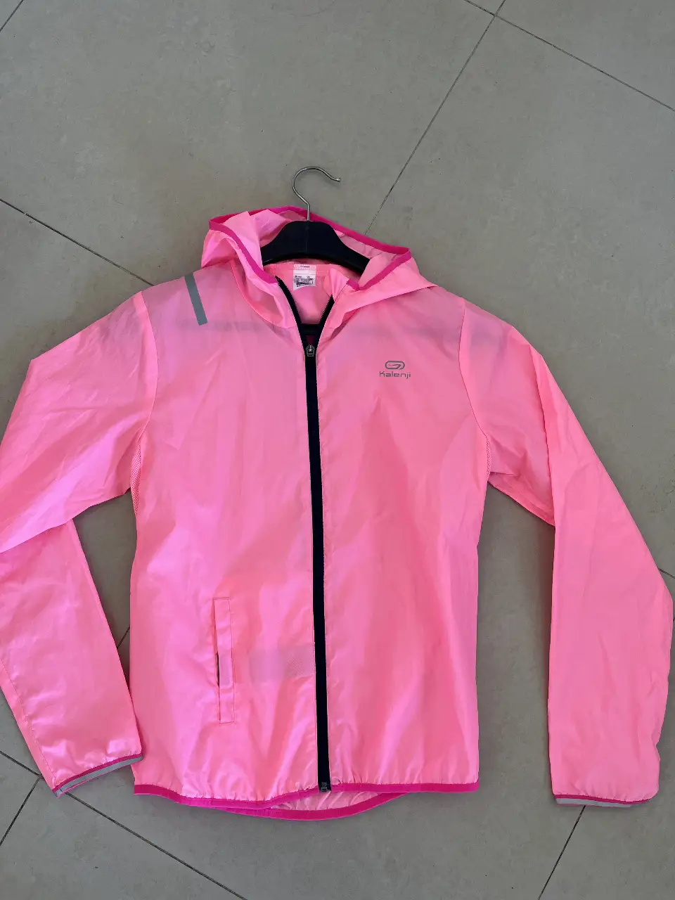 Campera rompevientos rosa para mujer de la marca Kalenji. Ideal para running y actividades al aire libre. Con capucha y cierre, es liviana y fácil de guardar. Talle 12 años.