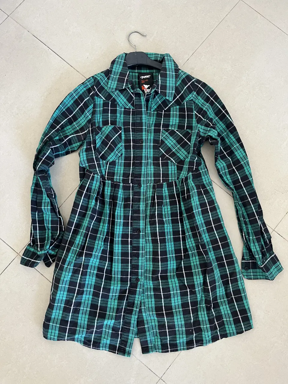 Vestido camisa a cuadros en tonos verde y negro, con detalle de entalle en la cintura. Ideal para un look casual y moderno.