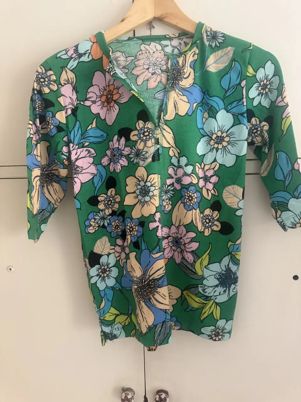Blusa de manga 3/4 con estampado floral en tonos verdes, azules, rosas y amarillos. Ideal para un look fresco y primaveral.