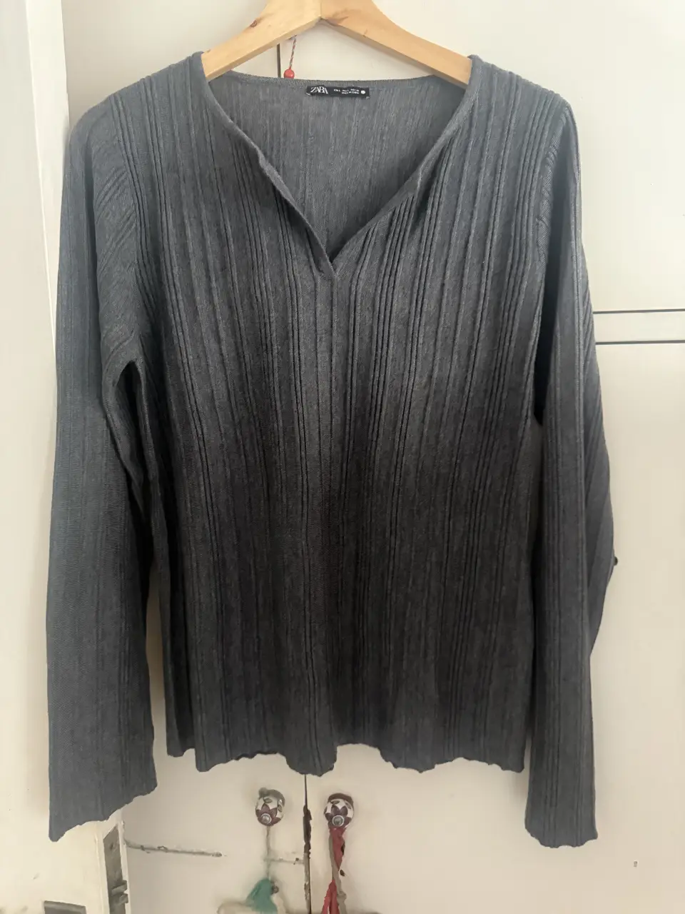 Sweater gris de tejido acanalado con cuello en V. Ideal para un look casual y cómodo.