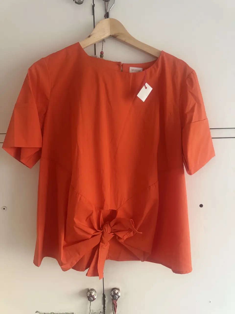 Blusa naranja con detalle de lazo en la parte delantera. Ideal para un look casual y fresco.