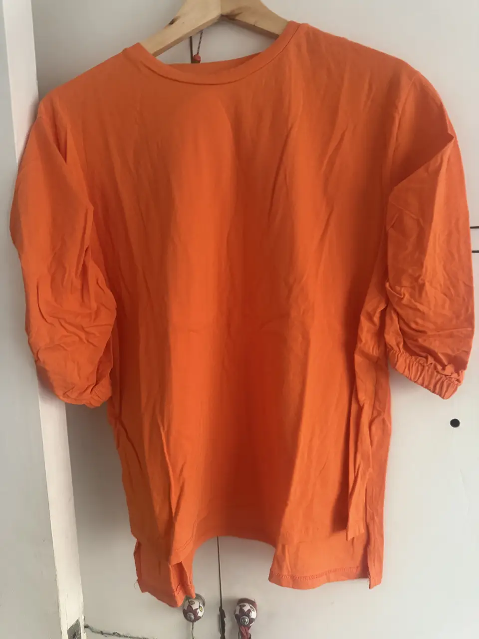 Remera naranja de manga corta con detalle de fruncido en los puños. Ideal para un look casual y cómodo.