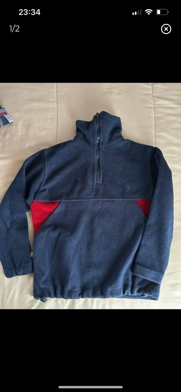 Buzo polar azul marino con detalles en rojo. Cuello alto con cierre y logo "CARBON" en la espalda. Ideal para el invierno.
