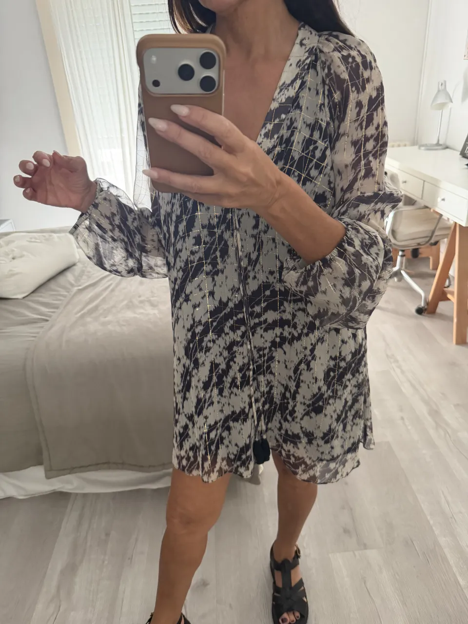 Vestido corto estampado con detalles dorados. Posee mangas largas y escote en V. Ideal para un look casual y chic.