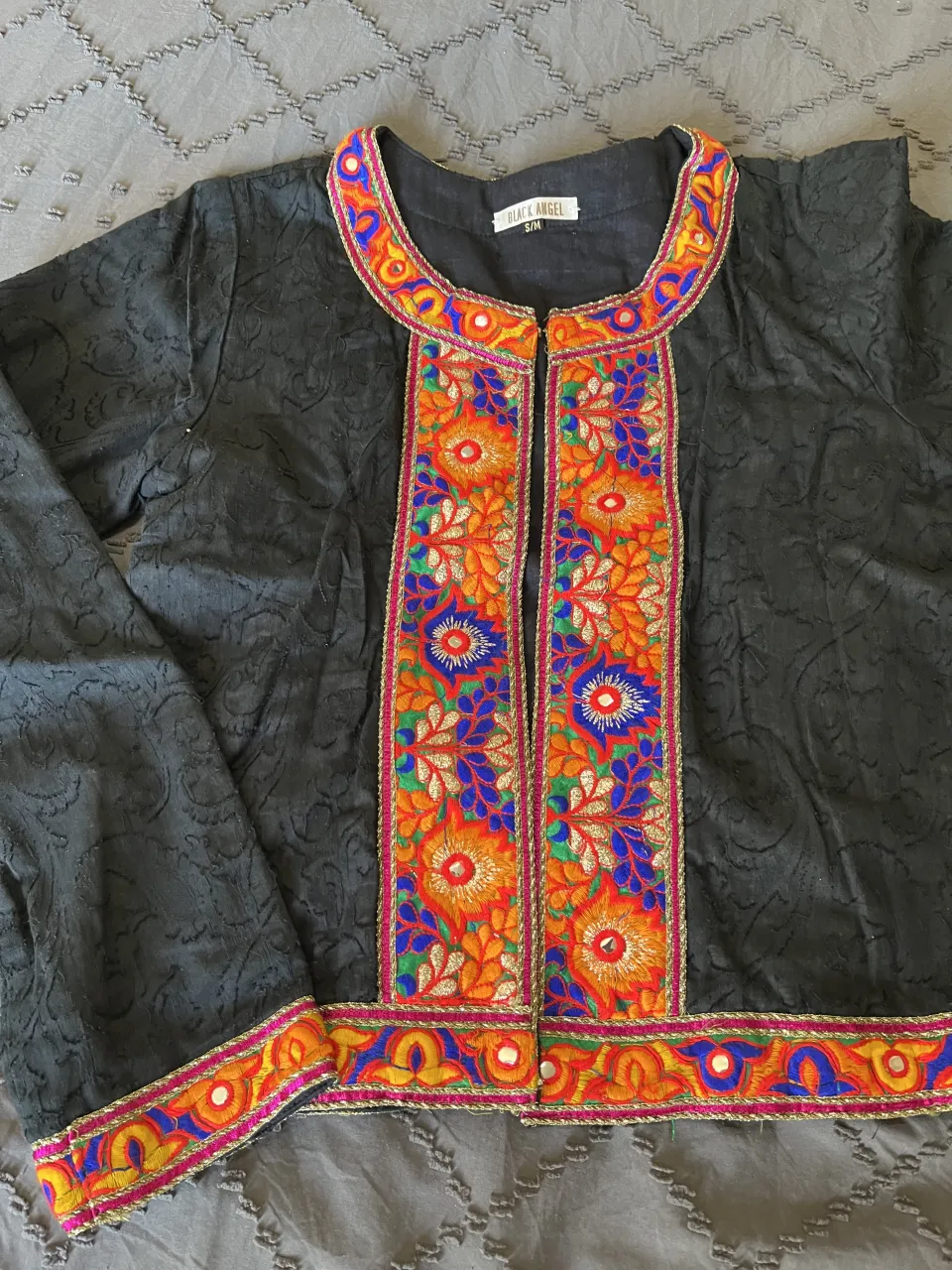 Campera negra con bordados coloridos y detalles de hilo dorado. Ideal para darle un toque vibrante a tu look.