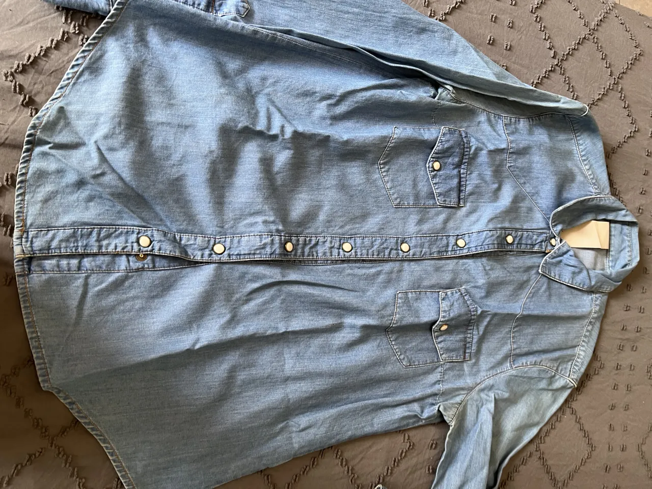 Camisa de jean clásica, ideal para un look casual y canchero. Perfecta para combinar con jeans o pantalones de vestir. Su diseño atemporal la hace una prenda versátil para cualquier ocasión.