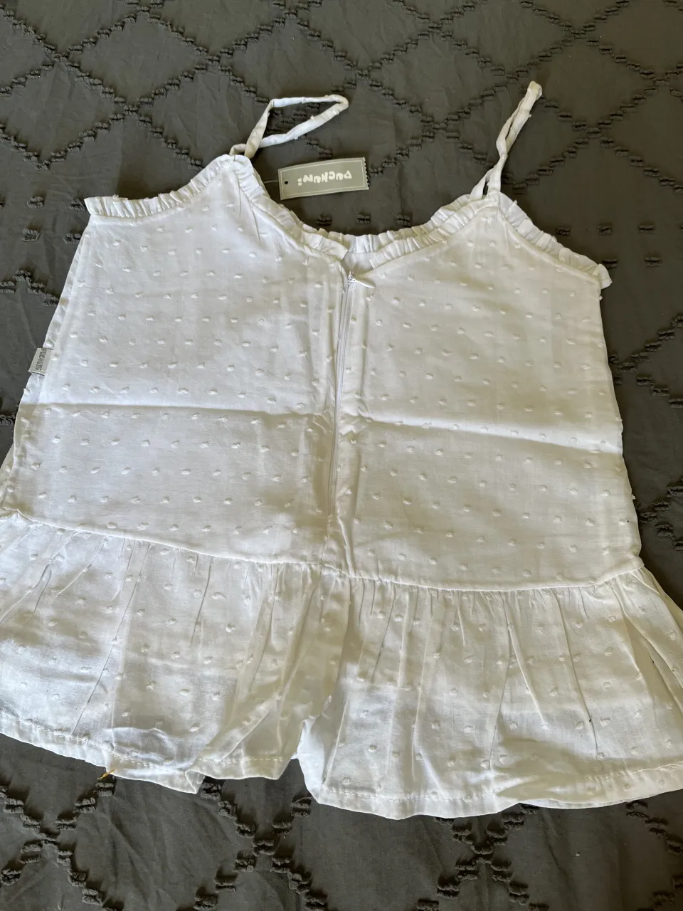 musculosa blanco de algodón con puntitos bordados y volados. Tiene tiras finas y cierre al frente. Ideal para días de calor. talle 12