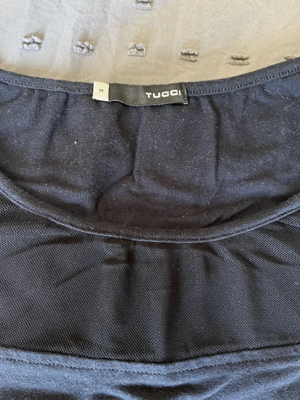 Remera negra de manga corta con detalles de mesh en la parte superior. Ideal para un look casual y moderno.