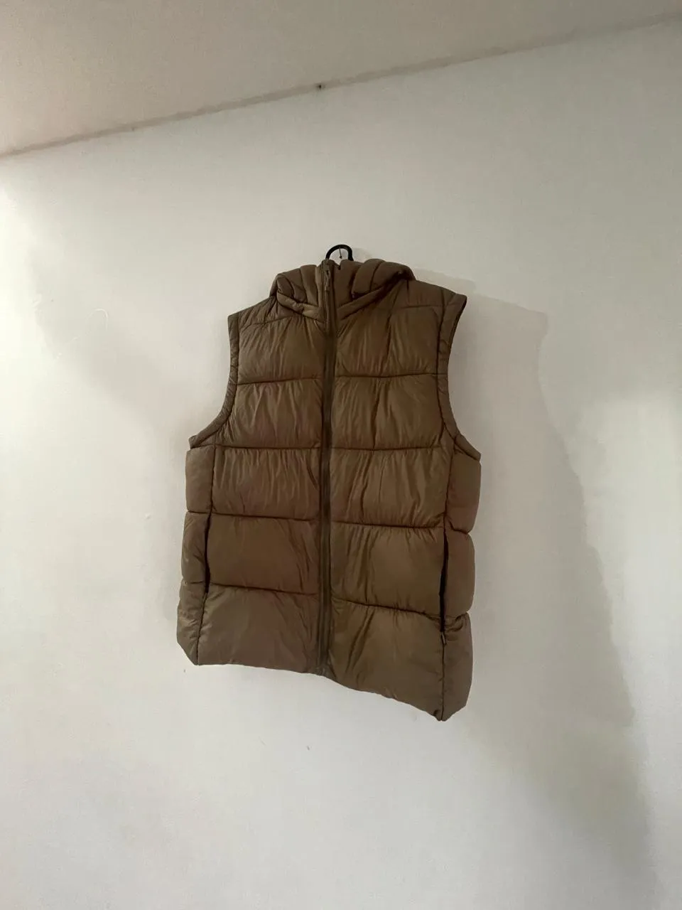 Chaleco acolchado con capucha y cierre al frente. Posee bolsillos laterales con cierre.