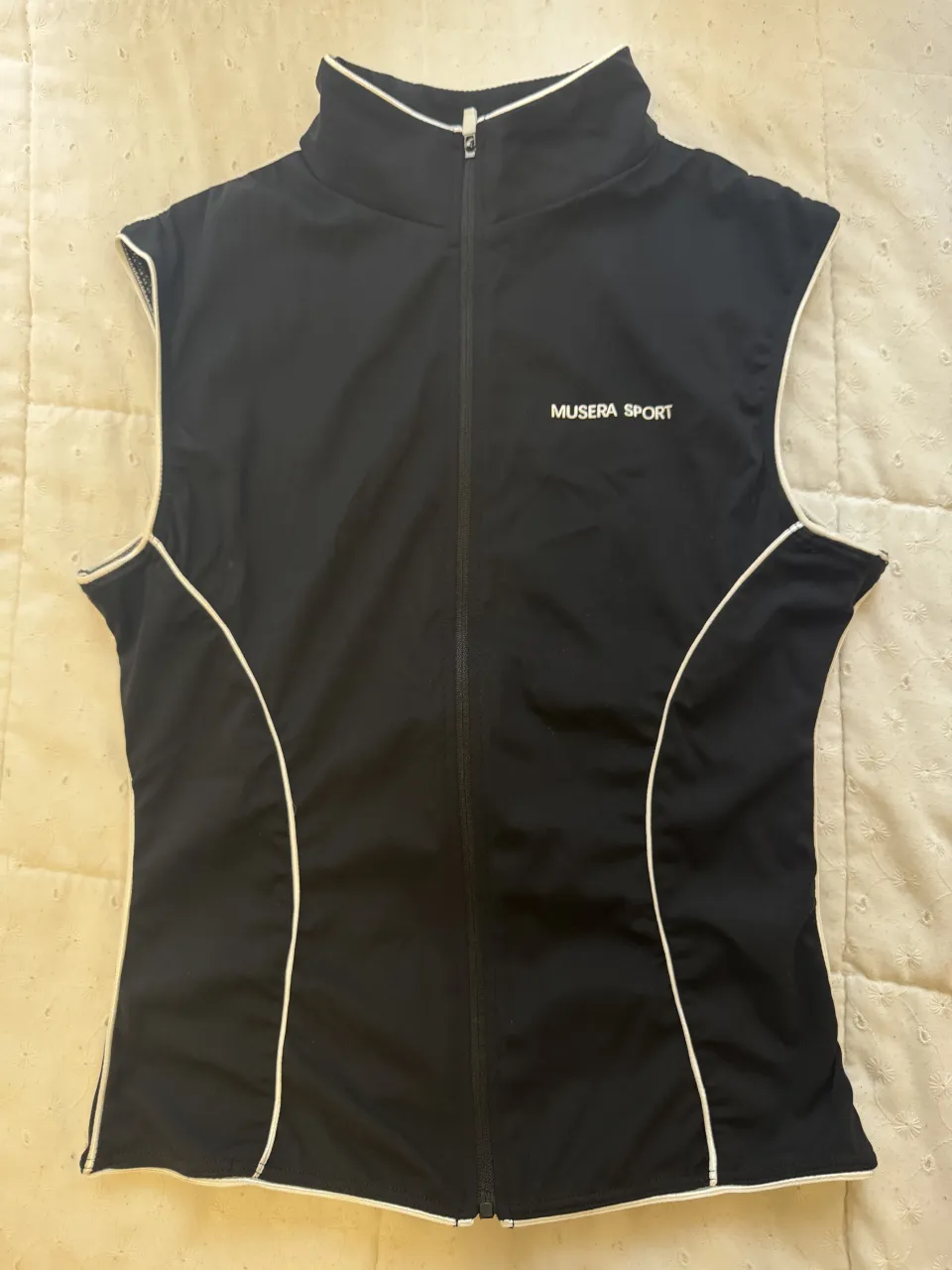 Chaleco deportivo negro con vivos blancos y logo blanco en el frente.