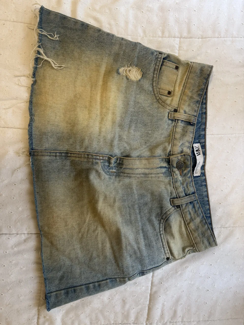 Pollera de jean corta con roturas y borde deshilachado. Lavado desgastado.