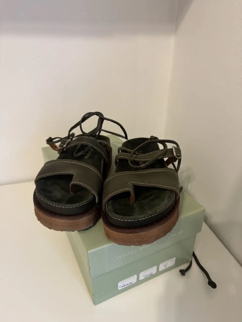 Sandalias de cuero verde con plataforma marrón. Diseño con tira para el dedo y hebilla ajustable. Ideales para un look casual y cómodo.