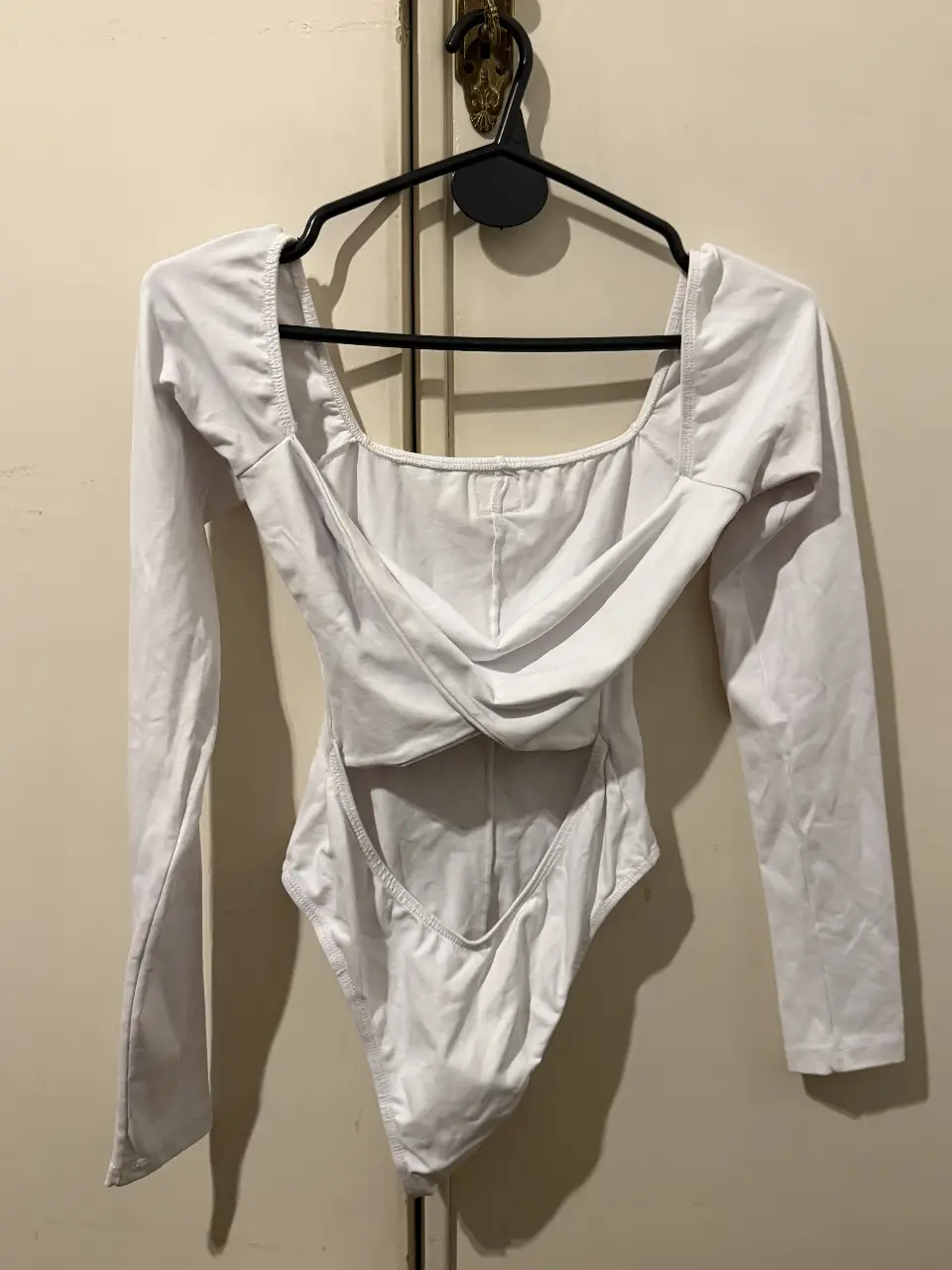 Body blanco de manga larga con diseño cruzado en la parte delantera y espalda descubierta. Ideal para un look moderno y elegante.
