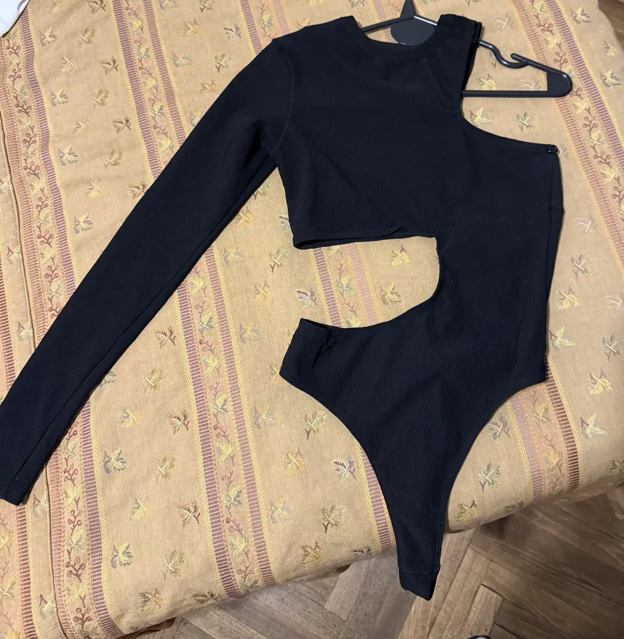 Body negro de diseño asimétrico, con una manga larga y un corte en el hombro. Ideal para un look moderno y audaz.