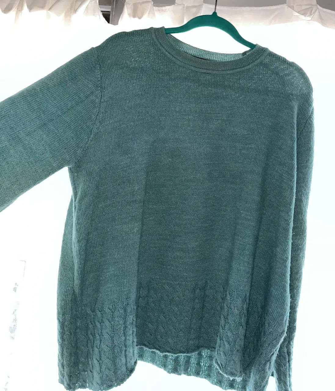 Sweater de cuello redondo en color celeste/verde agua, con detalle de tejido en la parte inferior. Ideal para un look casual y cómodo.