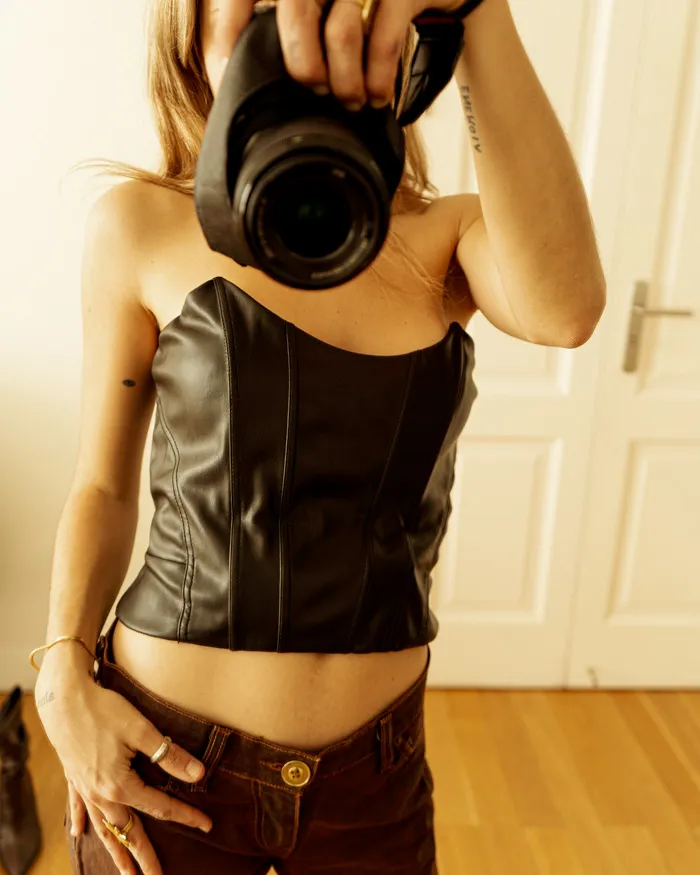 Top corset de cuero sintético negro, con costuras verticales que estilizan la figura. 