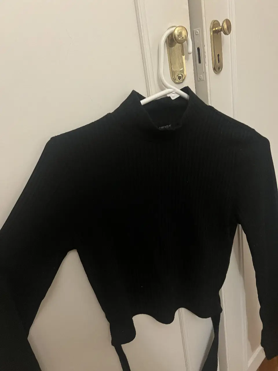 Top negro de manga larga con cuello alto y espalda descubierta.
