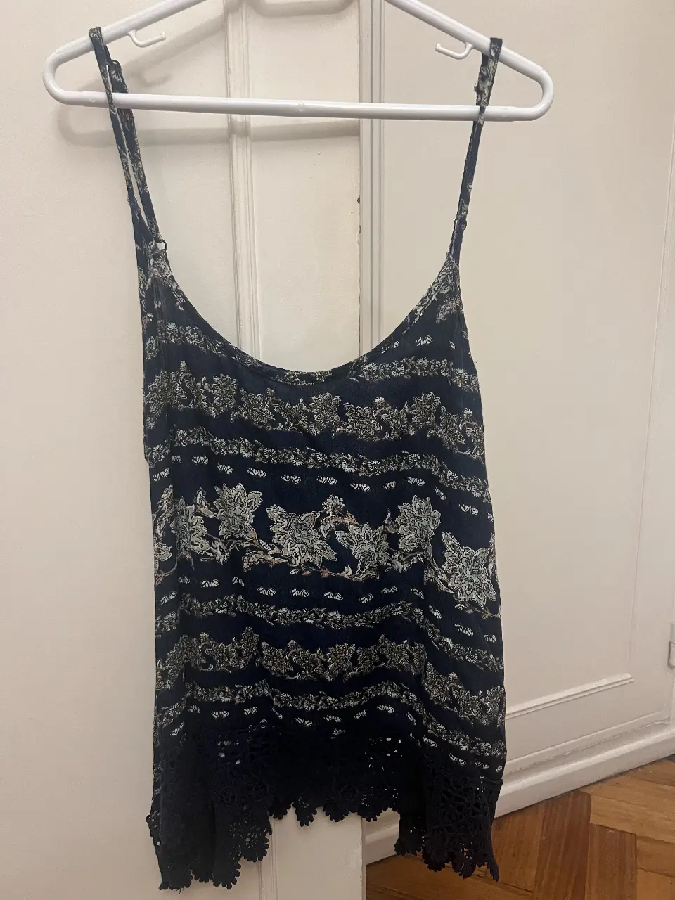 Top de mujer con estampado floral en tonos azules y blancos. Diseño con tirantes finos y detalle de encaje en el borde inferior. Ideal para un look   bohemio.