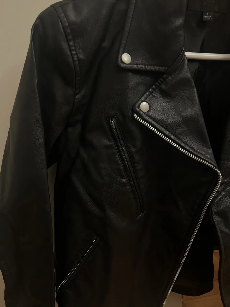 Campera  de cuero sintético negra, con cierre y detalles metálicos.