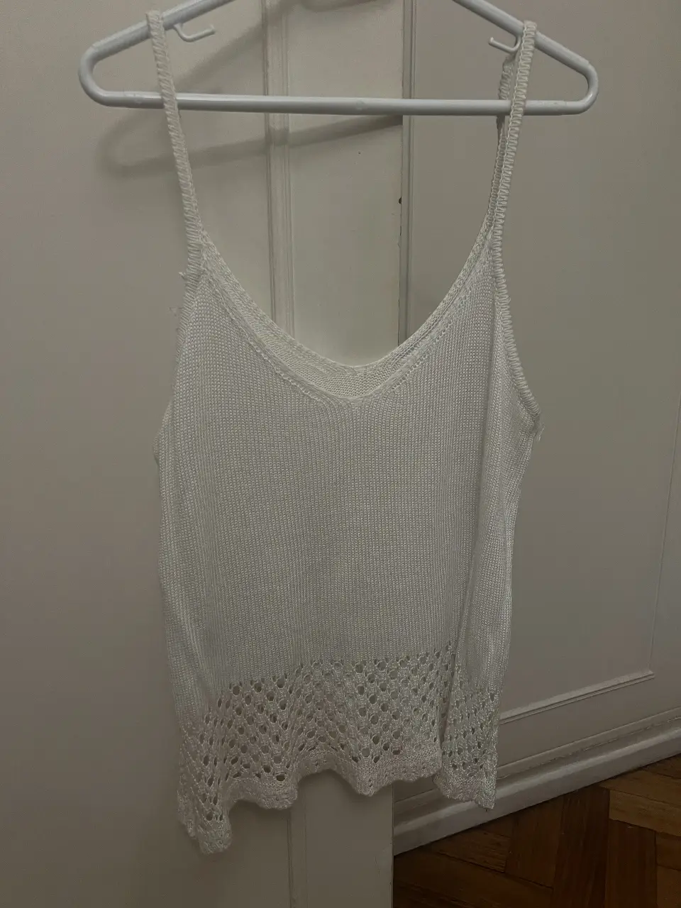 Musculosa de tejido calado en color blanco, ideal para el verano. Con escote en V y detalle calado en el bajo.
